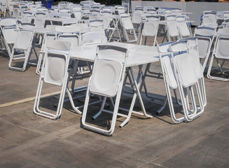 Groups of White Collapsible Chairs and Tables for the Event