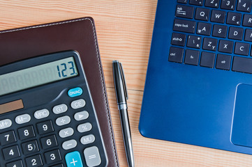 Calculator, notebook and laptop on a wooden table