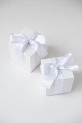 wo white square boxes with silk ribbon on white background