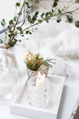 Interior tray decoration with burning candle, mimosa flowers and branches