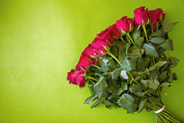 Festive background with a bouquet of red roses on a color monophonic background, a card for the holiday. Beautiful red roses, near the place for the inscription.