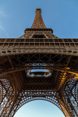 Detail of truss of Eiffel Tower bottom view. Detail bottom view of Eiffel Tower on the blue sky background in sunset light.