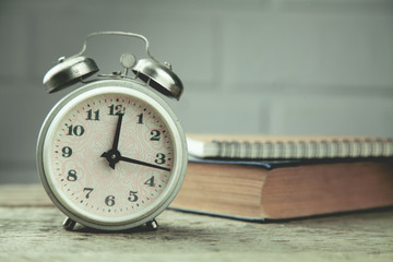 alarm clock and book on the wooden table
