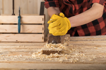 Close up of a carpenter planing a plank of wood with a hand plane