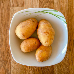 Four ptatoes in a whhite bowl