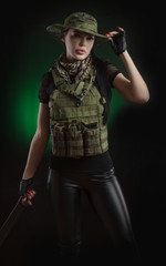 the girl in military special clothes posing with a gun in his hands on a dark background in the haze