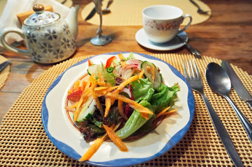 Mixed salad containing red lettuce on plate and table setup with tea at Log Cabin Restaurant in Sagada Town, Mountain Province, Philippines