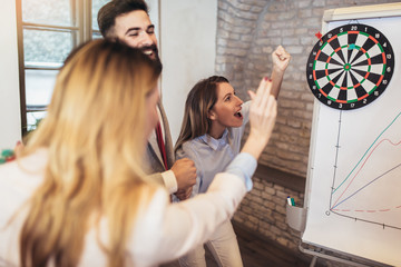 Business people making team training exercise during team building seminar, play darts. Indoor team...