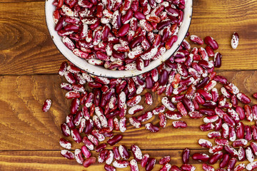 Raw kidney beans in white old enameled bowl on wooden table