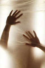 Hands through the clear film.Beautiful delicate feminine hands. A symbol of illusiveness and unreality. Warm gamma, warmth, sun