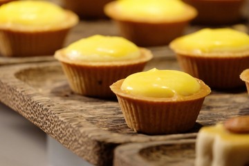 In selective focus of a row cheese tartlets on wooden tray and selling in the whole foods market