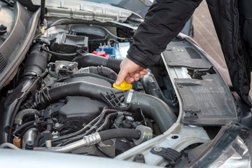 Man checking oil level in car engine.