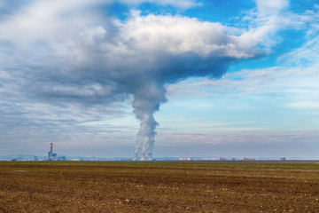 Fototapeta na wymiar Cooling towers of nuclear power plant (NPP) Jaslovske Bohunice (EBO) in Slovakia. Clouds of thick smoke from chimneys on blue sky at winter day. Cooling towers of power plant with water steam.