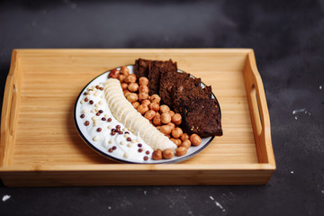 Closeup of healthy Breakfast plate with yogurt with chocolate chips, banana, rye bread and hazelnut