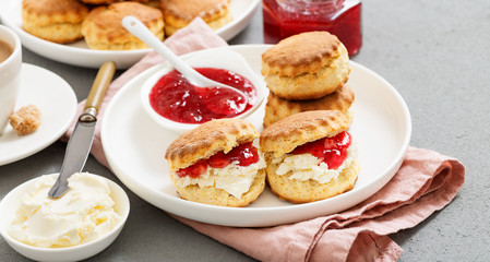 Traditional British Scones with clotted cream, strawberry jam and a cup of coffee.
