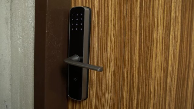 4K, woman pressing digital numbers to open wood door and go into the house. Unlocking blue numbers in electronic door guard. Girl is opening the smart security door of the room. Technology home-Dan