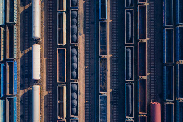 Aerial view of colorful freight trains on the railway station. Wagons with goods on railroad. Heavy industry. Industrial conceptual scene with trains. Top view. Photo captured with drone.