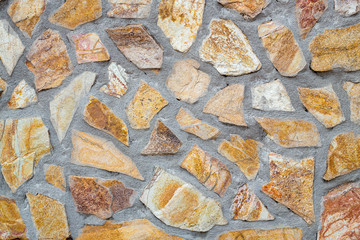 Pattern of decorative brown stone wall. Old castle wall background. Random size rock structure. Neatly stacked rough cut stone wall with concrete connection. Masonry wall of multicolored blocks.