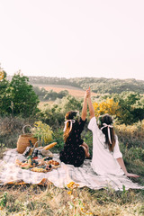 Two best friends on picnic in hte field holding hands in freedom concept