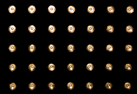Behind the scenes of a television production, this is a panel of MR16 bulbs against a black background producing warm glowing light.