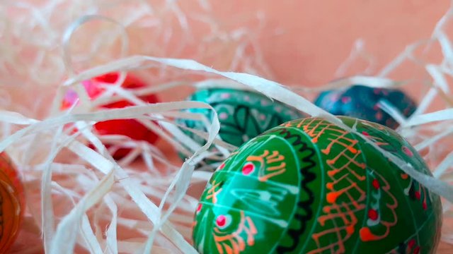 Happy Easter concept: painted multicolored decorative Easter eggs among decorative straw. The straw moves slightly in the wind.