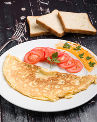 filled omelette with cheese and tomato on white plate