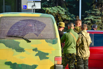 Military soldiers inspect civilian cars to prevent terrorist attacks.