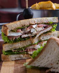 tasty chicken club sandwich with fries on wooden table