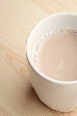 Hot homemade cacao in white cup at wooden background