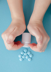 Woman's hands created a heart shape. White pills. Mock up for special offers as advertising or other ideas. Medical and healthcare concept. Copy space. Empty place for text or logo on blue background