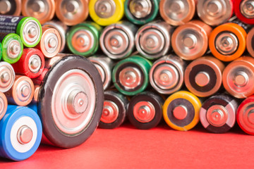 Stack of used batteries on a red background