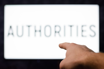 Male`s hand points to tv set with writing AUTHORITIES