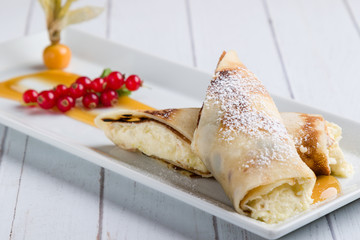 european pancakes, sweet crepe with topping on white long plate