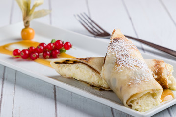 european pancakes, sweet crepe with topping on white long plate