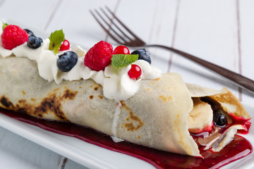 european pancakes, sweet crepe with topping on white long plate