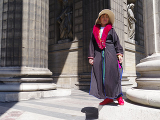 Femme avec un mateau noir et une écharpe rouge posant devant les colonnes de l'église de la...