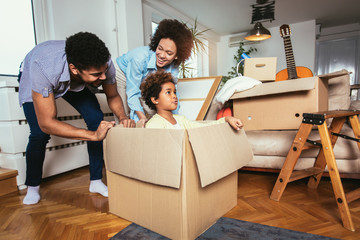 African American family, parents and daughter, unpacking boxes and moving into a new home, having fun.