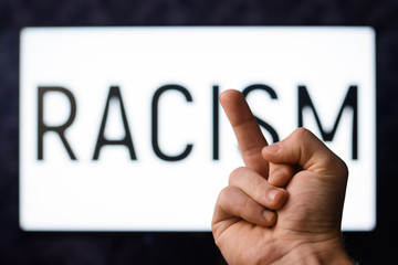 Say no to racism. Caucasian male showing middle finger to inscription RACISM