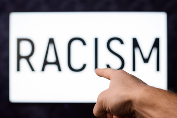 Man pointing to a screen with inscription RACISM in order to show source of many problems in USA. People should stop thinking that their race is better than other races
