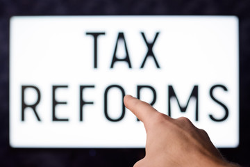 Man pointing to a screen with inscription TAX REFORMS in order to inform people about reforms