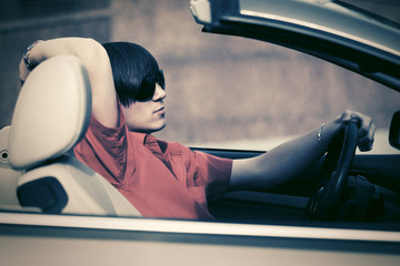 Naklejka premium Young man in sunglasses driving convertible car
