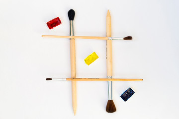 Play tic tac toe with paints. Brushes artist, with a wooden handle make up the grid.