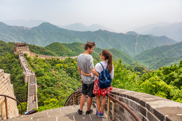 Travel tourists people sightseeing in China travel vacation. Happy interracial couple enjoying Great wall of China landscape near Beijing city. Asia travel summer holidays together. © Maridav