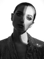 Black and white portrait of trendy girl with hair pulled back and stylish makeup in a shining dress...