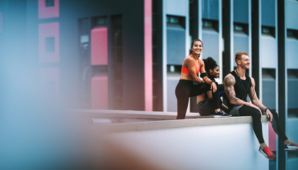 Fitness people relaxing after workout sitting on rooftop