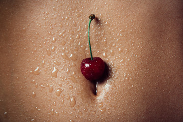 Wet cherry on the female body. Sexy woman concept.
