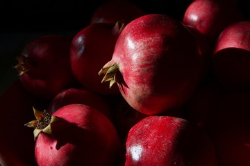 A whole scarlet pomegranate on a black background close-up.