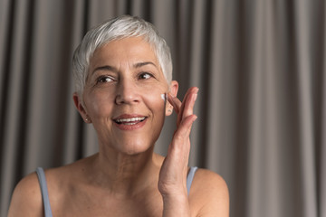 Beautiful woman applying anti age cream