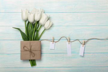 A bouquet of white tulips and envelope with a stickers with clothespins on a rope and blue wooden boards