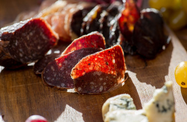thin slicing jerked sausage and other snacks on a wooden board